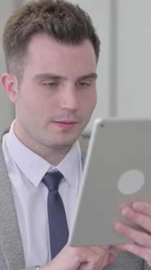 Smiling Man in Suit Using Tablet for Work