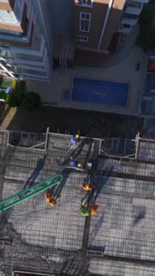 Vertical Video of Workers Erecting Walls and Pouring Concrete Foundations While a Crane Assists on