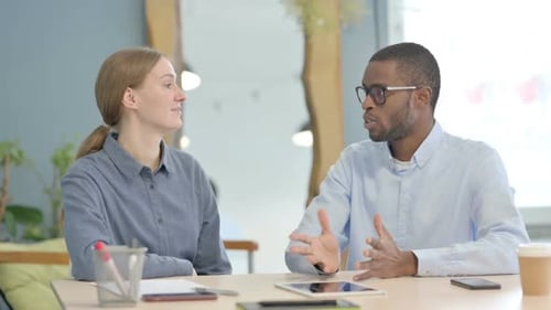 Talking Young Business People Sitting in Office