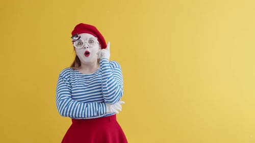 Mime une femme dans un t-shirt rayé, des lunettes et des rêves de béret en levant les yeux et en secouant la tête, sur un o