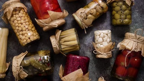 Closed Pickling Jars with Various Vegetables on Stone Table