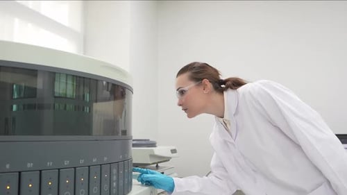 Female Scientist Operating Automated Diagnostic Machine in Lab