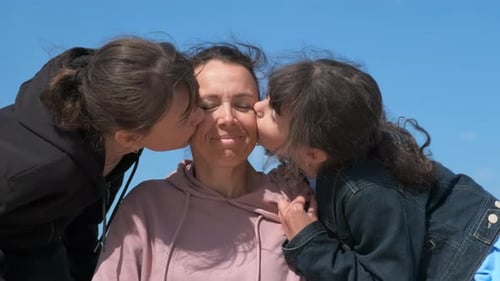 Mother Receives Kisses From Children Outdoors