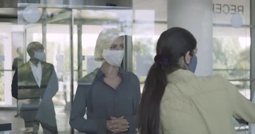 Business people arriving in corporate office lobby wearing protective face mask
