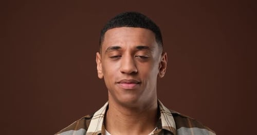 Young African American Man Satisfied Happy Guy Looking at Camera Standing Over Brown Studio