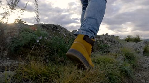 Der Mensch geht die Berge entlang bis zum Gipfel. Tourist in Boots Going