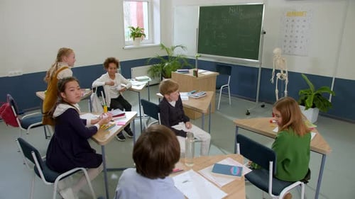 Elementary School Class Children Communicate with the Teacher Answering Question