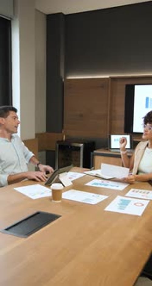 Vertical video: Diverse coworkers reviewing charts explaining graphs on monitor in conference room