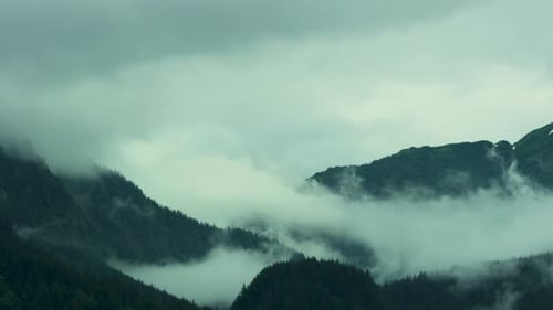 The white clouds move slowly over the green mountain tops.