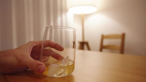 Hand Holding Glass of Whiskey with Ice