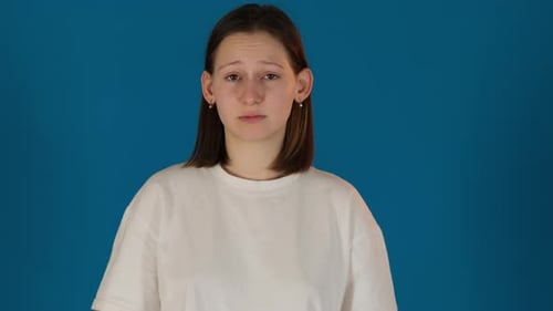 Young Woman Reacts to Something Against Blue Backdrop