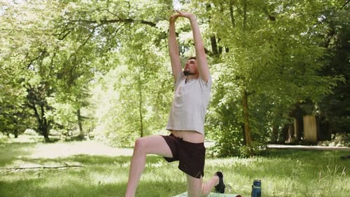 Athletic Sporty Fit Man Doing Workout Yoga Breathing Exercise on Sports Mat Raising Hands in Park