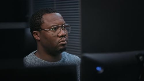 Man Working with Computers in Dark Office Setting