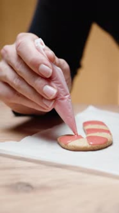 Vertical video. Homemade gingerbread cookies in the shape of candy canes for Christmas. The woman co