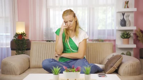 Woman Sitting on Couch Looking Concerned