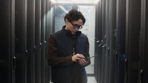 Portrait of Asian Data Center Engineer Holding Tablet in Server Corridor
