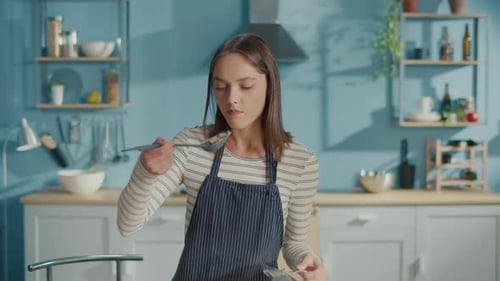Woman Tastes Food in Kitchen