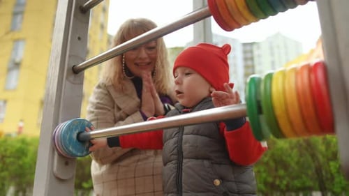 Slow Motion Mom Rejoices When Her Little Son Plays Abacus While Standing Outdoors on a Spring Day at