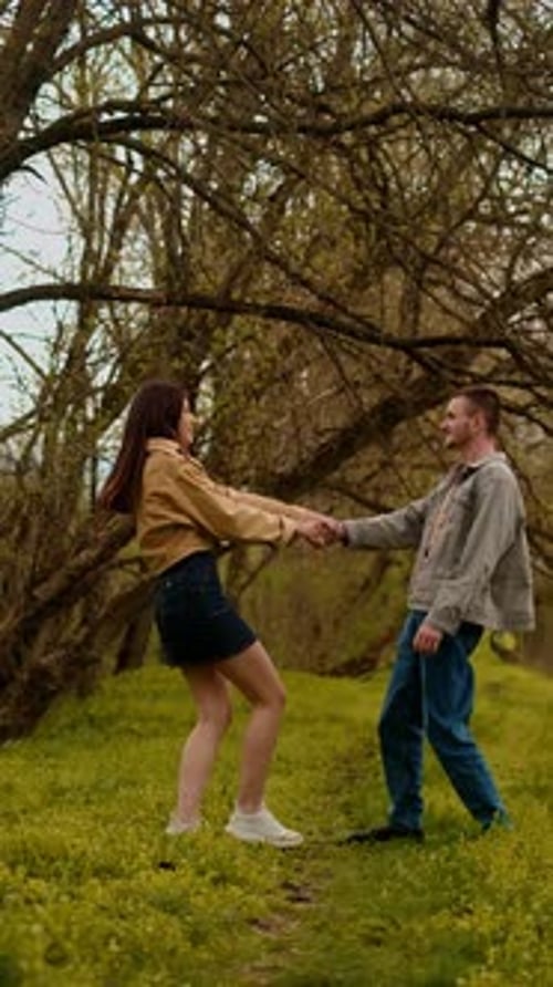 A young couple holding hands run through the forest, embodying an active lifestyle and tourism. Spor