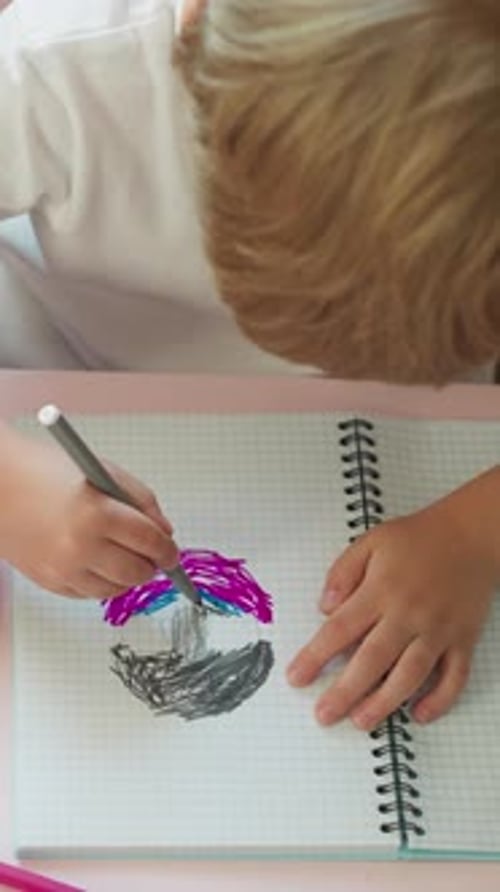 Child Drawing Colorful Umbrella in Notebook
