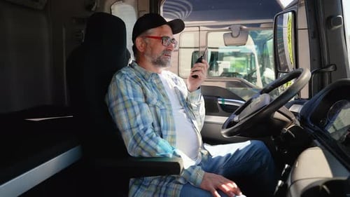 Senior Truck Driver Speaks on the Radio Walkie Talkie with Supervisor Before Leaving