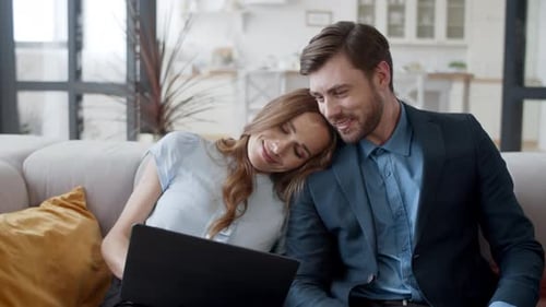 Affectionate Couple Relaxing on Sofa with Laptop