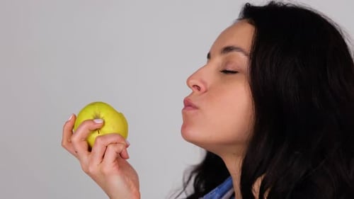 Smiling Lady Enjoying Fresh Yellow Apple While Biting It Isolated on Grey Background Copy Space