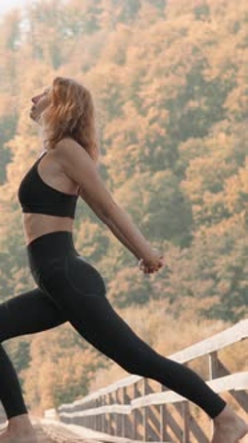 Une pose de yoga stimulante exécutée avec grâce sur un pont en bois entouré d'un paysage automnal