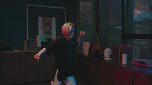 Young Woman Dancing in Room with Colored Lighting