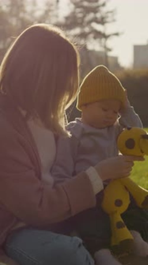 Vertical video Mother and child enjoy a sunny day on a blanket in the park