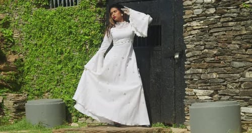 A child in a vintage wedding gown strolling through the ruins of an old fort.