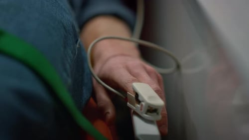 Paciente masculino que comprueba el nivel de oxígeno en sangre del paciente con un oxímetro en un coche de ambulancia