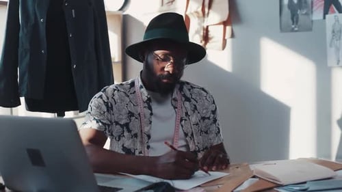 Man Designing Fashion at Desk in Bright Studio