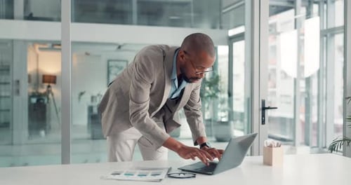 Man Works at Desk on Laptop in Office