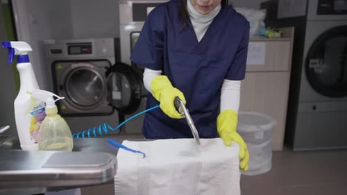 Female Worker Drying Towel After Removing Stain At Laundry Shop. slow motion shot