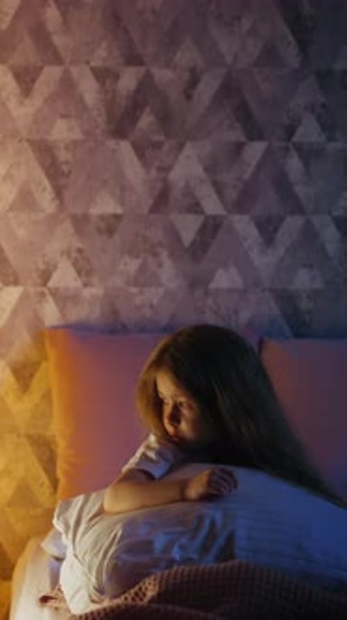 Offended Child with Pillow Looks at Play House with Lamp