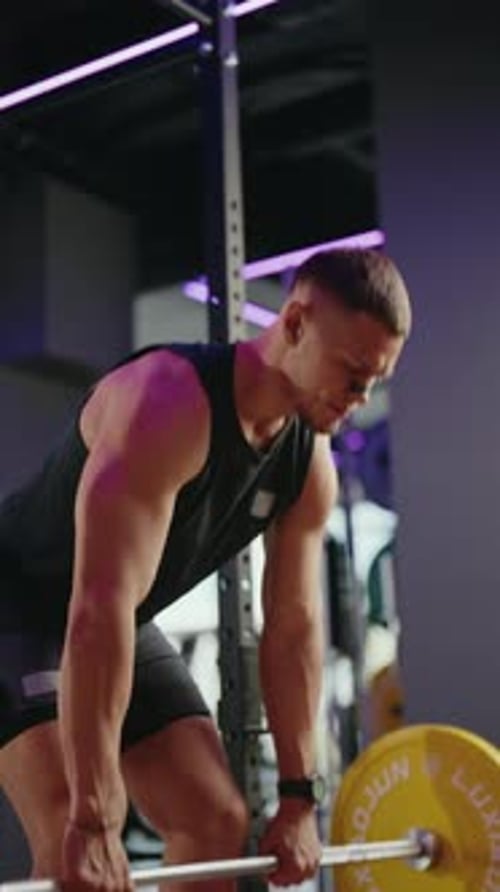 Muscular Man Deadlifts in Modern Gym with Purple Lighting