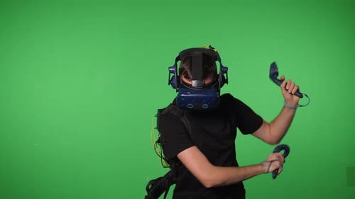 A Man Uses Virtual Reality Glasses to Play in a Studio on a Green Background
