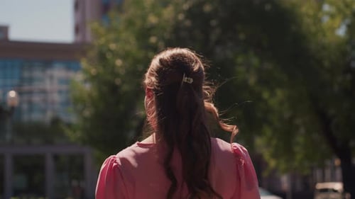 Woman in Pink Dress Wanders City Streets Under Sunlight Contemplative Female Figure in Pink Attire
