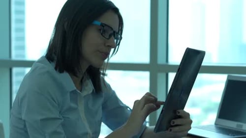 Young Businesswoman Browsing Internet on Tablet Computer in Office 30s