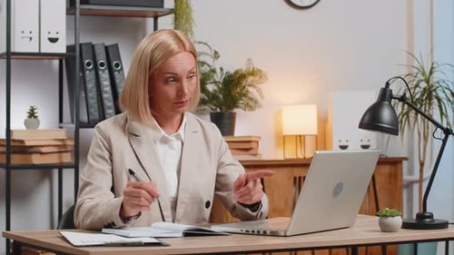 Businesswoman Writing Down or Taking Down Notes While Attending Online Office Meeting at Home Office