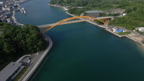 Slow cinematic drone tilt up over Seto Inland sea with yellow bridge
