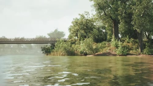 Serene Riverbank View with Lush Greenery and a Rustic Bridge on a Calm Day