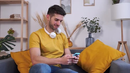 Young Adult Relaxing with Smartphone at Home