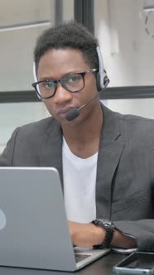 Young Man Working on Computer Wearing Headset