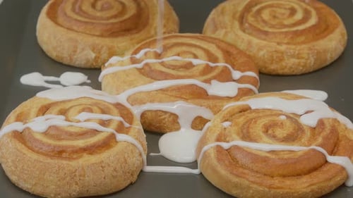 Icing Being Drizzled on Sweet Cinnamon Rolls