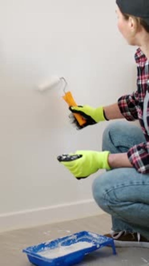 Mujer pintando la pared en una habitación nueva durante la renovación de su casa
