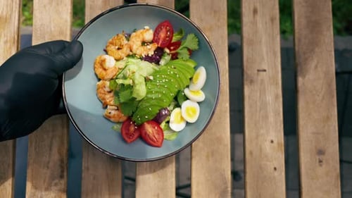 Vertical Video Close Up in a Restaurant on the Street on Plank Table a Blue Plate with a Warm Salad