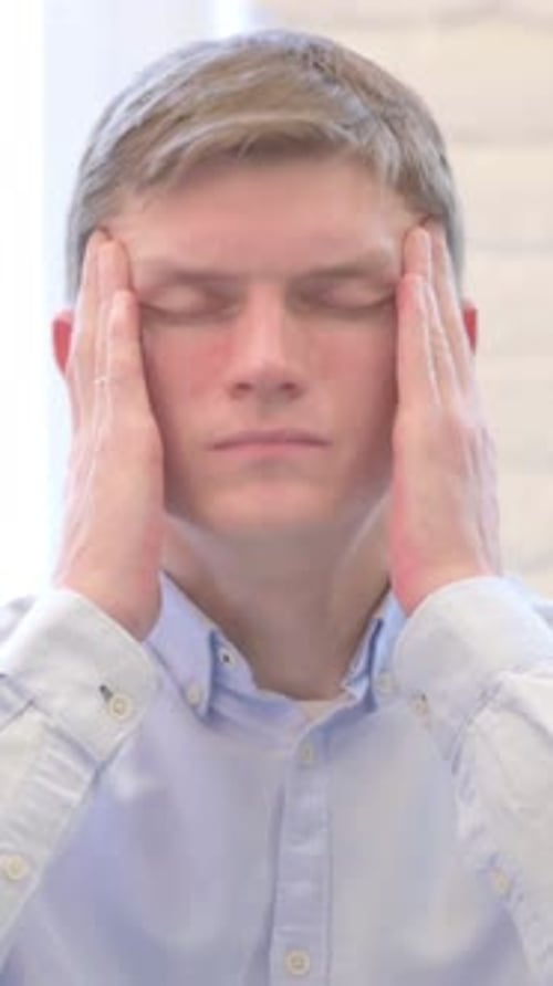 Young Blond Haired Man Massaging Temples in Distress