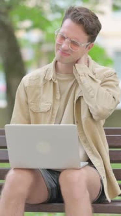 Man with Neck Pain Works on Laptop in Park